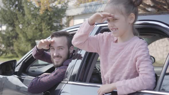 Portrait Little Girl on the Back Seat of the Car Leaned Out of the Window Close Up. The Father Is on alt