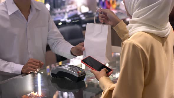Asian Muslim Woman Using a Mobile Phone For Payment 01