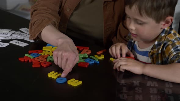 Mom teaches her son how to say the words on the cards at home at the table