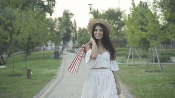Happy Beautiful Woman Elegant White Dress Walking Shopping Bags Smiling Passing Camera alt