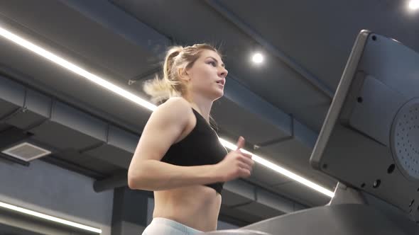 Young Beautiful Blonde Woman Is Doing Sports in the Gym