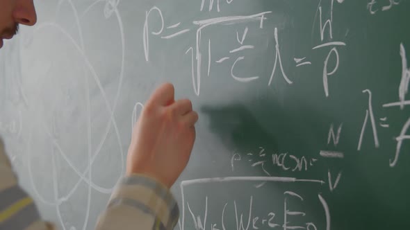 Close Up Teacher Man Hand Writing Math Formulas on Chalkboard with White Chalk alt
