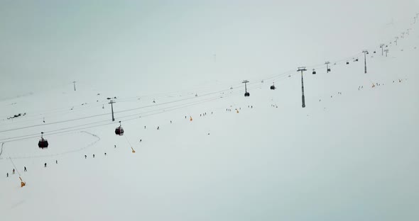 Aerial shot of skiing gondola lifts in heavy snowing and foggy weather alt