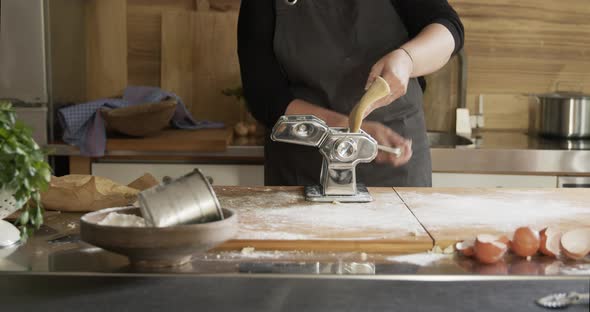 Woman using pasta machine while making dough for Maultaschen alt