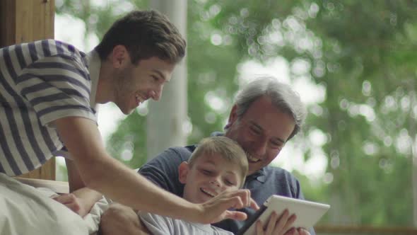 Boy with father and grandfather using digital tablet alt