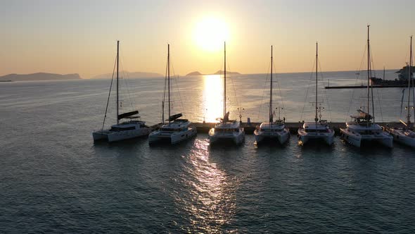 Catamaran and Sail Yachts Anchored at Bay on Deep Blue Sea Water on Sunrise