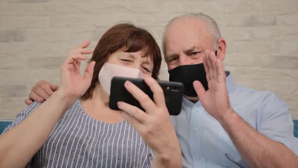 Senior Couple Talking on Video Chat with Their Children and Wearing a Medicinal Mask. alt