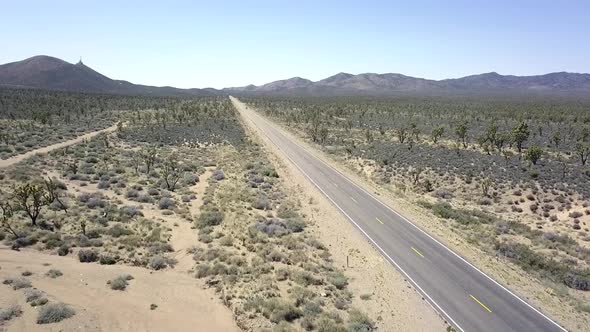 An empty grade black road in no man's land. Spectacular aerial view flight fly backwards drone foota alt