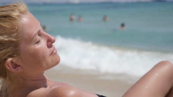 Woman  enjoys sunbathing on beautiful  beach slow motion 1920X1080 HD footage - Caucasian blonde gir