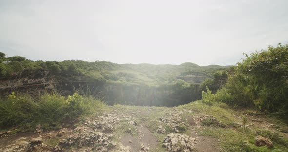 Dolly Shot of Walking Towards the Cliff Edge with Reveal of Stunning Blue Lagoon and Steep Ocean alt