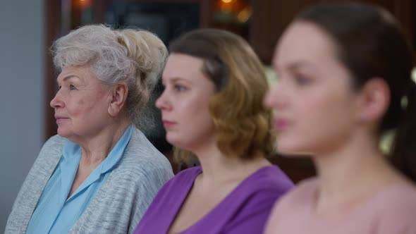 Portrait of Happy Senior Woman Turning to Camera Smiling with Blurred Daughter and Granddaughter at alt