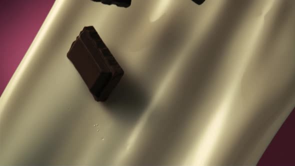 Chocolate pieces blend with pouring milk in slow motion.