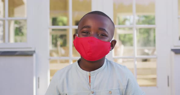 Portrait of african american boy wearing face mask outdoors on a bright sunny day alt