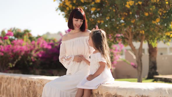 Happy Travelers Woman and Her Cute Little Daughter in White Dresses Enjoying Beautiful Tropical City alt