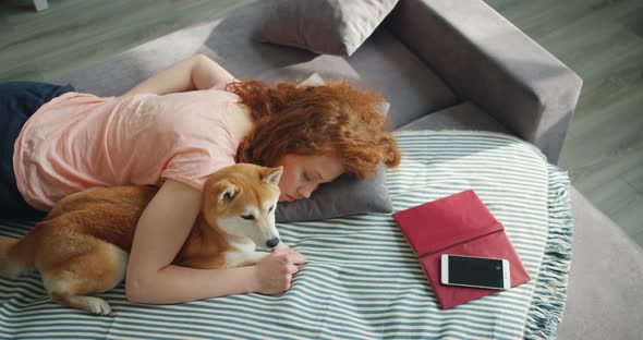 Attractive Young Woman Sleeping at Home on Sofa Hugging Cute Shiba Inu Dog alt