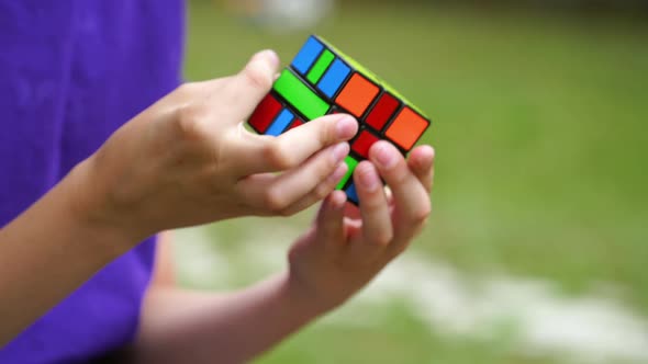 Rubik's cube in boy's hands on blurred background. Clever child brainstorms his mind alt