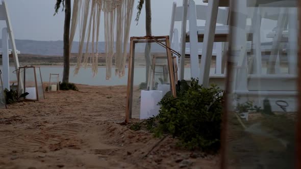 Close up of a candle panning left to reveal a beautiful beach ceremony set up during golden hour. Lo alt
