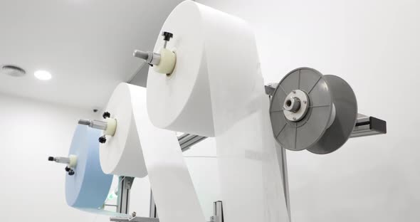 Machine With Large Rolls Of Non-woven Fabric Material For Medical Mask Manufacturing. low angle, slo alt