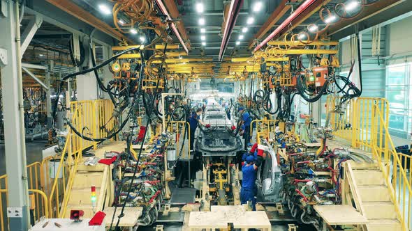 Factory Workers Assembling a Car Body at a Car Plant alt
