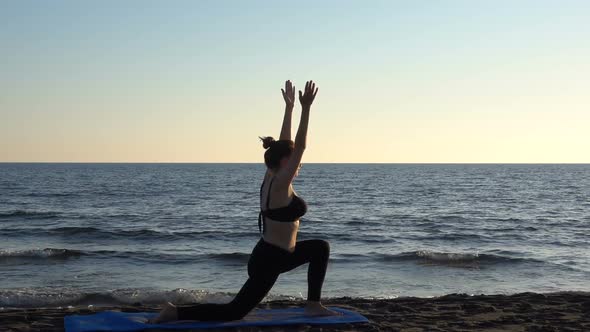 Young Caucasian Woman Practicing Yoga on the Beach Near Calm Sea, Sunrise Background.