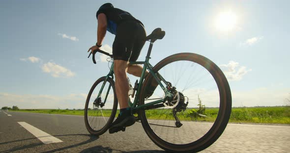 A Sportsman on a Bicycle is Standing on the Pedals and Developing Great Speed alt