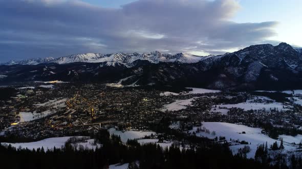 Evening in the mountains. Christmas winter landscape. Illuminated alpine city covered with snow.