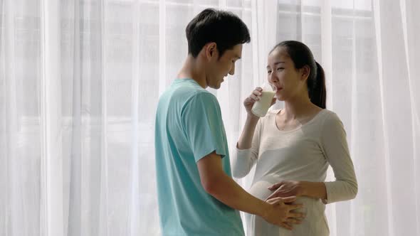 Man send milk and listening sound flex in pregnant woman belly. alt