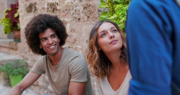 Afroamerican Man Smiling outdoor.Three Tourists Talking, Smiling, and Having Fun Near a Brick Wall alt