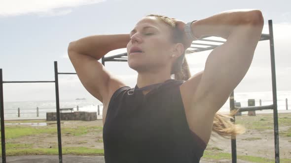 Sporty Caucasian woman exercising in an outdoor gym during daytime alt