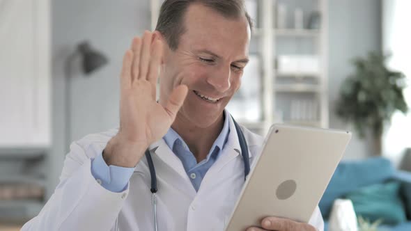 Senior Doctor Discussing with Patient via Video Chat on Tablet alt