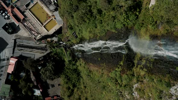 Cascada de la Virgen With Rainbow Flowing Down On Rocky Cliff With Vegetation In Baños de Agua Santa alt