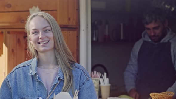 Happy woman buying noodles in box in food booth