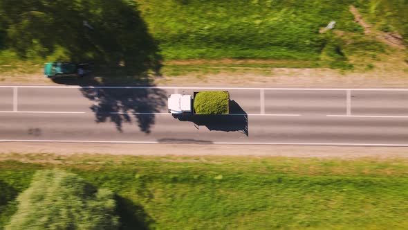 A Truck Loaded with Crushed Grass is Driving Along the Road Aerial View alt