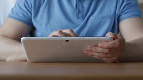 Hands Of Young Man With A Tablet Pc At The Table At Home