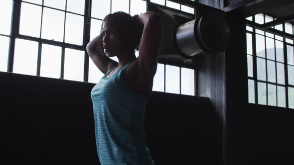 African american woman resting breathing heaviily after exercising in an empty urban building alt