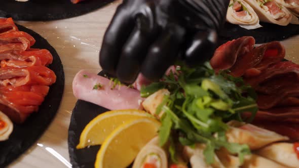 The Chef's Hand Decorates a Dish with Ham Lemon and Sandwiches with Red Caviar with Microgreens alt