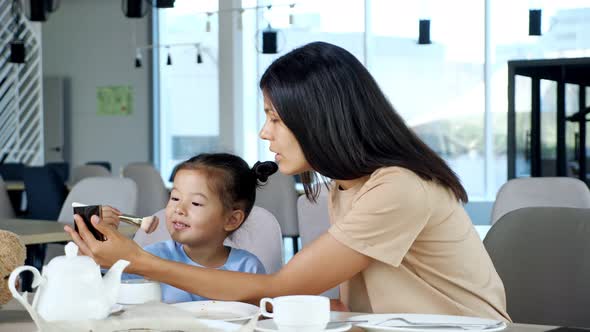 Young Mother Holds Mirror and Girl Moves Brush with Powder alt
