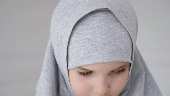 Young Muslim Teen Girl in Hijab Shyly Looking at Camera and Smiling alt