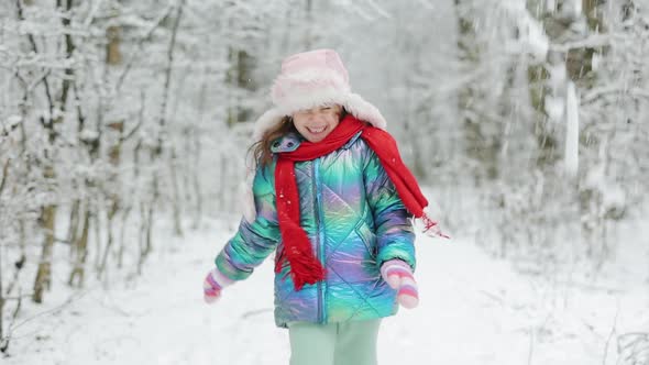 Little Happy Girl in Winter Clothes is Having Fun Running in Snowy Winter Day