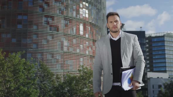 Businessman Walking on Street. Confident Executive Holding Documents Outdoors alt