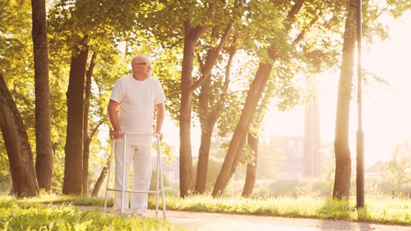 Disabled old man is walking with a walker. Handicapped patient in the park. alt