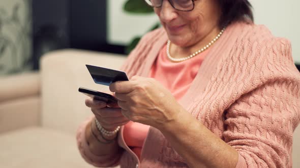 Senior Woman Using Mobile Phone Credit Card Shopping Online At Home. Mature Woman Online Banking. alt