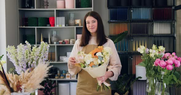 Smiling Woman florist with a Beautiful Bouquet of fresh Flowers in the Store Looks at Camera. alt