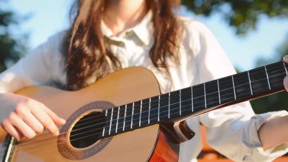 Teen Girl Plays on Guitar and Sings in the City Park