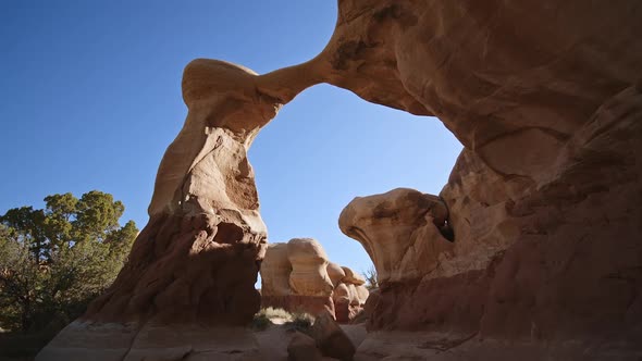 Hiking through and looking up at sandstone arch in the desert alt