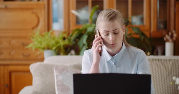 Home Office Concept - Woman Talking on Mobile Phone and Use Laptop. alt