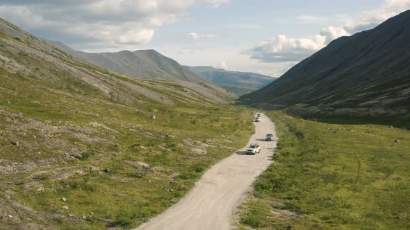 SUVs are Driving on a Dirt Road in the Valley of the Khibiny Mountains alt