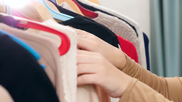 CLoseup of Female Hands Moving Along Clothes Rack in Store and Choosing What To Buy or Wear alt