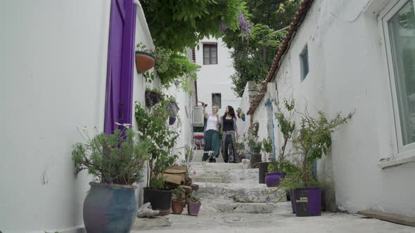 Two women walking down from a narrow street in Bozcaada Island Turkey alt