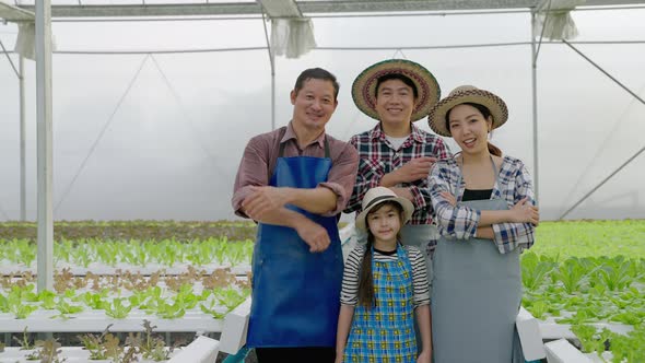 portrait of an Asian organic vegetable farmer family is standing and smiling confident